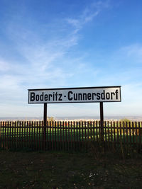 Information sign on wooden post against sky