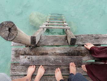 Low section of people standing on pier at lake