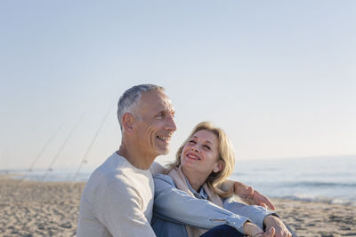 Smiling couple sitting at beach