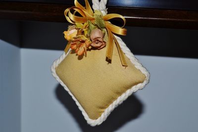 Close-up of cushion with flower decoration hanging against wall