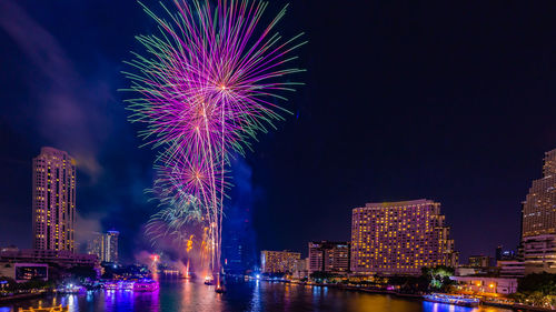 Firework display over illuminated buildings in city at night