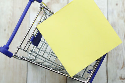 Directly above shot of small shopping cart and adhesive note on table