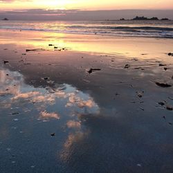 Wet beach against sky during sunset