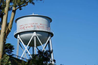 Low angle view of water tower against clear blue sky