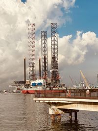 Cranes at commercial dock against sky