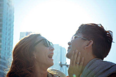 Happy young couple against sky in city