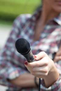 Midsection of women holding microphone