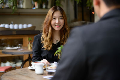 Portrait of smiling young woman with drink in restaurant