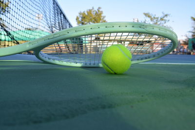 Close-up of ball and tennis racket at sports court