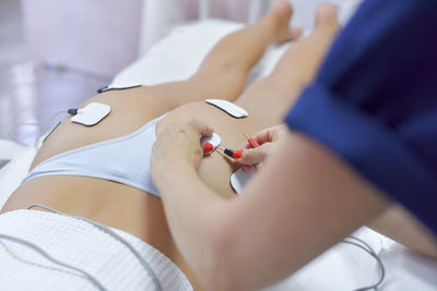 Midsection of woman holding hands on bed