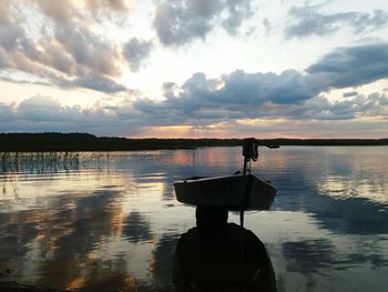 Silhouette boat in lake against sky during sunset