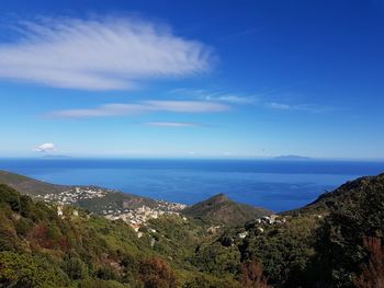 Scenic view of sea and mountains against blue sky