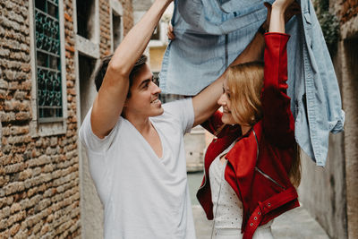 Young man and woman standing by wall