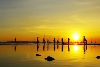 Silhouette people in sea against yellow sky during sunset in east nusa tenggara indonesia