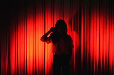 Rear view of man with arms outstretched standing against red light