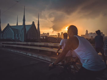 Man riding bicycle against sky during sunset