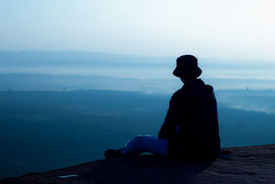 Man sitting and watching the sunrise in the morning on the cliff