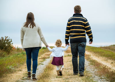 Rear view of young family walking away on country road