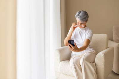 Side view of young man sitting on bed at home