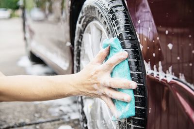 Cropped hands of man washing car tire