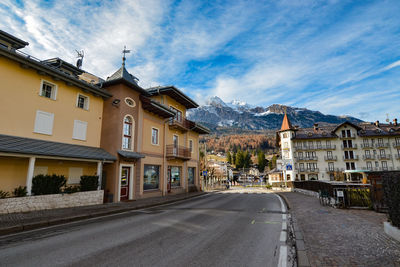 Road by buildings in city against sky