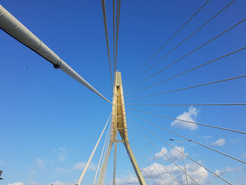 Low angle view of suspension bridge against blue sky