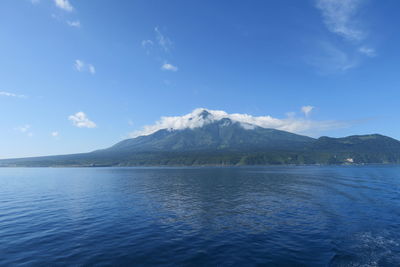 Scenic view of sea and mountains against blue sky