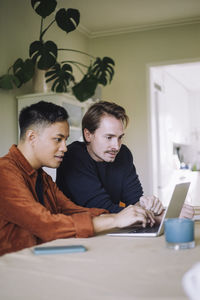 Multiracial gay freelancers working on laptop while sitting at home