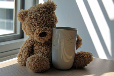 Close-up of mug and teddy bear on table