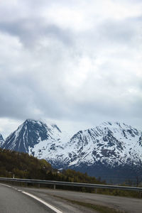 Road by snowcapped mountains against sky