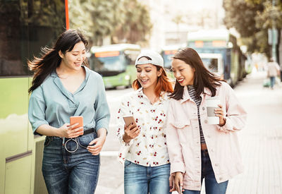 Portrait of smiling young woman using mobile phone in city