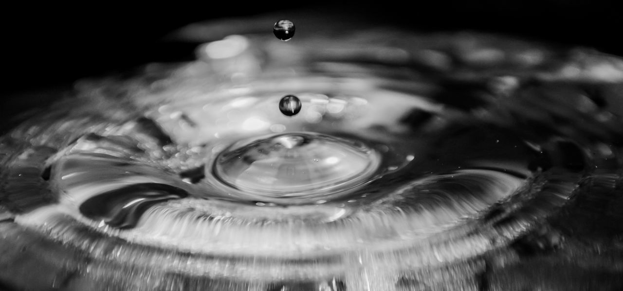 HIGH ANGLE VIEW OF DROP FALLING ON WATER IN DRINKING GLASS