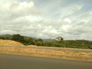 Road by trees against sky
