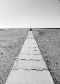 Footpath by sea against clear sky