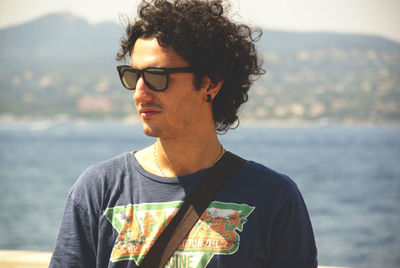 Portrait of young man standing against sea