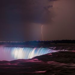 Scenic view of river against dramatic sky at night