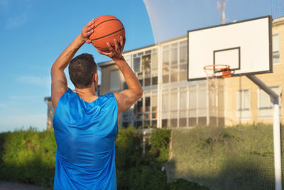 Low angle view of man playing basketball against blue sky