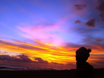 Silhouette woman on rock against sky during sunset