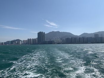 Scenic view of sea and buildings against clear blue sky
