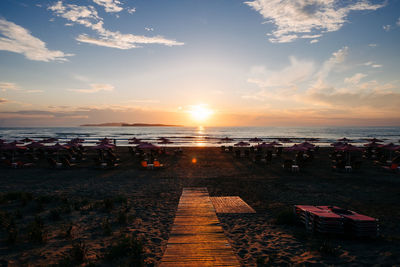 People on beach against sky during sunset