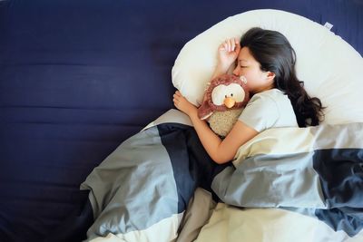 Directly above shot of girl sleeping on bed at home