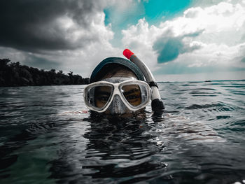 Close-up portrait of woman snorkeling in sea against sky
