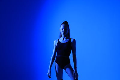 Young woman standing against blue background