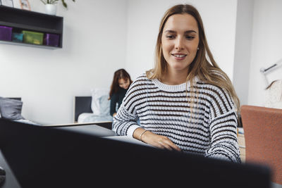 Portrait of young woman using laptop at home