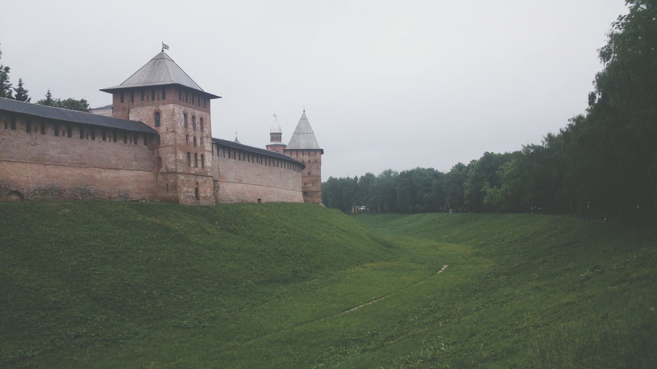 architecture, built structure, building exterior, grass, clear sky, copy space, tree, history, green color, sky, field, travel destinations, landscape, day, tranquility, nature, grassy, outdoors, famous place, tranquil scene