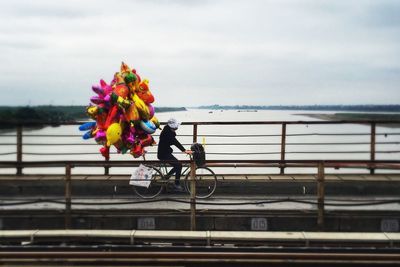 Side view of person riding bicycle with balloons