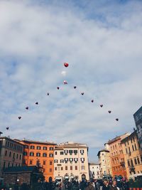 Low angle view of heart shape balloons over city at valentine day