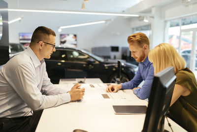 Salesperson advising couple in car dealership