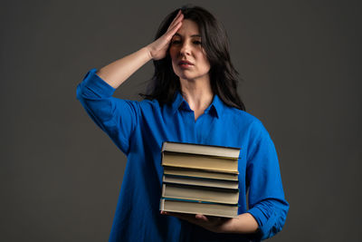 Young woman reading book against black background