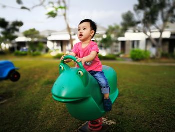 Cute boy sitting on play equipment at park